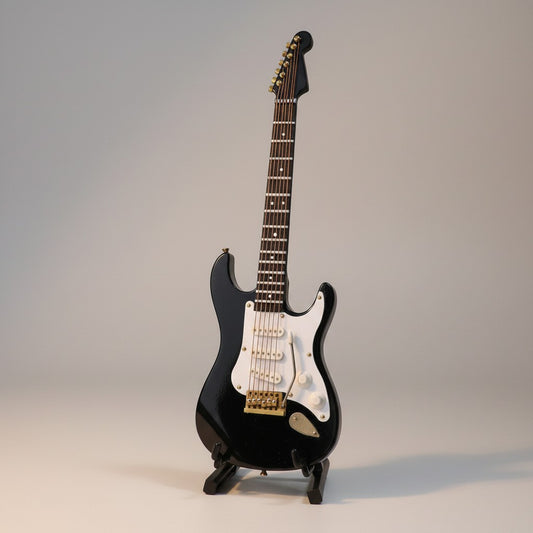 Regalos Ejecutivos Ortiz black electric guitar replica, 14cm, with white pickguard and gold hardware, on display stand.