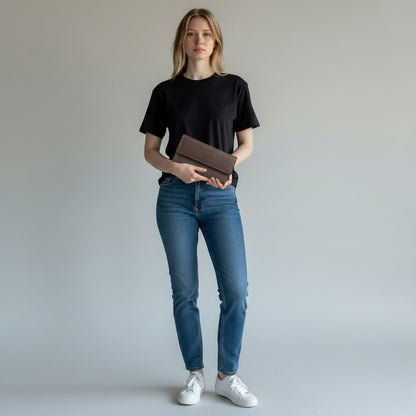 Regalos Ejecutivos Ortiz brown leather elongated wallet with snap closure held by a woman in a black t-shirt